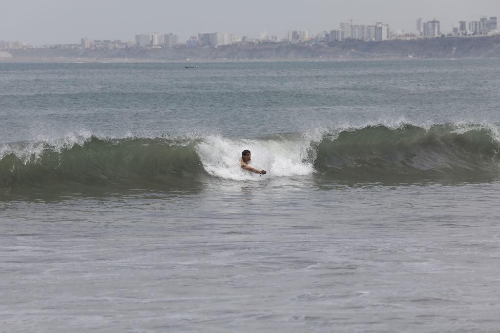 Una persona es llevada por una ola en una playa de la capital peruana