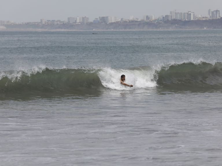 Una persona es llevada por una ola en una playa de la capital peruana