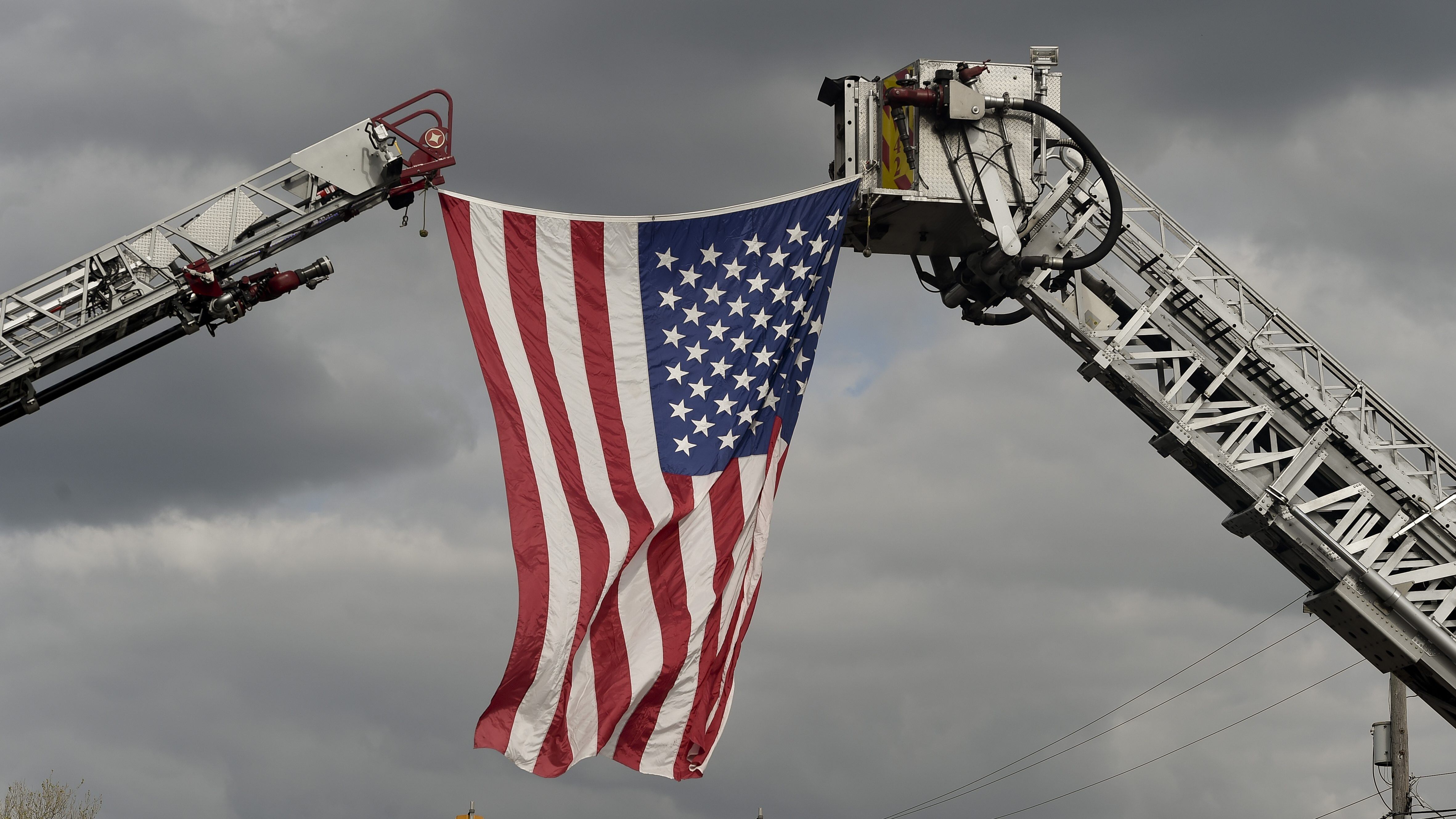 Sinking Spring, PA - May 21: On Penn Ave. in Sinking Spring where firefighters setup an arch with two ladder trucks to hang a flag over the road, during A procession for Exeter Township Fire Department Sergeant, and Iraq War veteran Jeremy Emerich, who died Thursday from complications with COVID-19. The procession traveled from Lehigh Valley Hospital to Bean Funeral Home in Sinking Spring. May 21, 2020 (Photo by Ben Hasty/MediaNews Group/Reading Eagle via Getty Images)