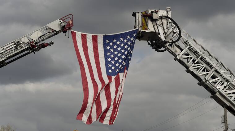 Sinking Spring, PA - May 21: On Penn Ave. in Sinking Spring where firefighters setup an arch with two ladder trucks to hang a flag over the road, during A procession for Exeter Township Fire Department Sergeant, and Iraq War veteran Jeremy Emerich, who died Thursday from complications with COVID-19. The procession traveled from Lehigh Valley Hospital to Bean Funeral Home in Sinking Spring. May 21, 2020 (Photo by Ben Hasty/MediaNews Group/Reading Eagle via Getty Images)