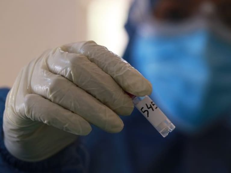 Dhaka, Bangladesh – June 24, 2020:  A medical official wearing protective stuffs as she holds up COVID-19 testing kit after collected sample from a resident to test for the COVID-19 coronavirus at a hospital in Dhaka, Bangladesh on June 24, 2020.