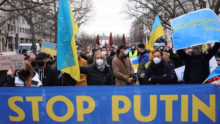 BERLIN, GERMANY - FEBRUARY 22: A woman holds a Ukrainian flag next to a banner reading stop Putin as youth groups protest Ukraine intervention with human chain in front of the Russian Embassy on February 22, 2022 in Berlin, Germany. Yesterday, Russia recognized two breakaway regions of eastern Ukraine as independent republics and said it would send troops in "peacekeeping functions," prompting widespread condemnation from Western governments. (Photo by Omer Messinger/Getty Images)