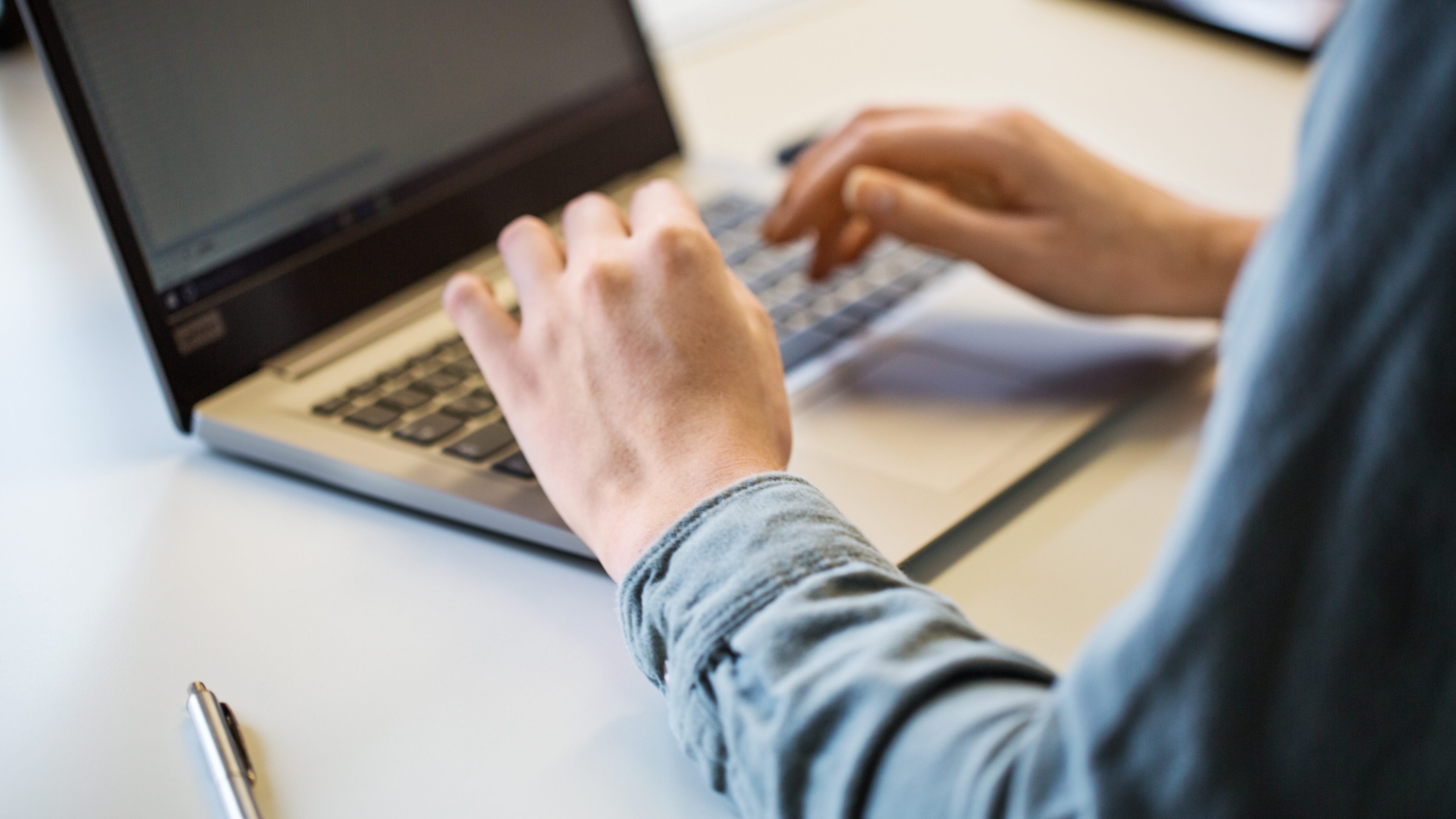 Close up of female hand using laptop on office table. Cropped shot of businesswoman working on laptop.
