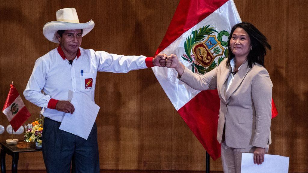 Peruvian rival presidential candidates Pedro Castillo (L), of the Peru Libre party, and Keiko Fujimori, of the Fuerza Popular party, bump fists during the signing of a 'pledge to democracy' ahead of the runoff vote, at the Peru Medical School in Lima on May 17, 2021. - The candidates took an oath coined the "Citizens Proclamation" that commits the winner of the June presidential election to defend democracy, fight COVID-19, defend the right to life, guarantee human rights and freedom of the press, as well as to leave the presidency after five years and not seek reelection. (Photo by Ernesto BENAVIDES / AFP) (Photo by ERNESTO BENAVIDES/AFP via Getty Images)