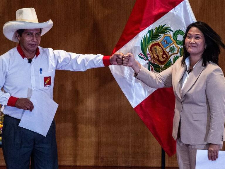 Peruvian rival presidential candidates Pedro Castillo (L), of the Peru Libre party, and Keiko Fujimori, of the Fuerza Popular party, bump fists during the signing of a 'pledge to democracy' ahead of the runoff vote, at the Peru Medical School in Lima on May 17, 2021. - The candidates took an oath coined the "Citizens Proclamation" that commits the winner of the June presidential election to defend democracy, fight COVID-19, defend the right to life, guarantee human rights and freedom of the press, as well as to leave the presidency after five years and not seek reelection. (Photo by Ernesto BENAVIDES / AFP) (Photo by ERNESTO BENAVIDES/AFP via Getty Images)