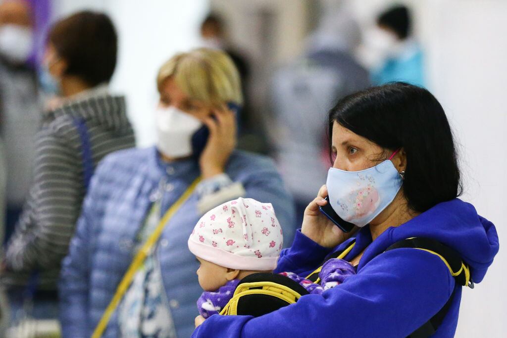 Una mujer y su hijo con mascarilla esperan en el aeropuerto de Vladivostok en Rusia