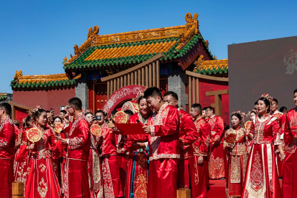 SHENYANG, CHINA - SEPTEMBER 22: Newly-wed couples attend a group wedding in traditional Chinese style under the witness of their families and friends in the South Square at Shenyang Imperial Palace on September 22, 2024 in Shenyang, Liaoning Province of China. (Photo by Cai Jingyu/VCG via Getty Images)