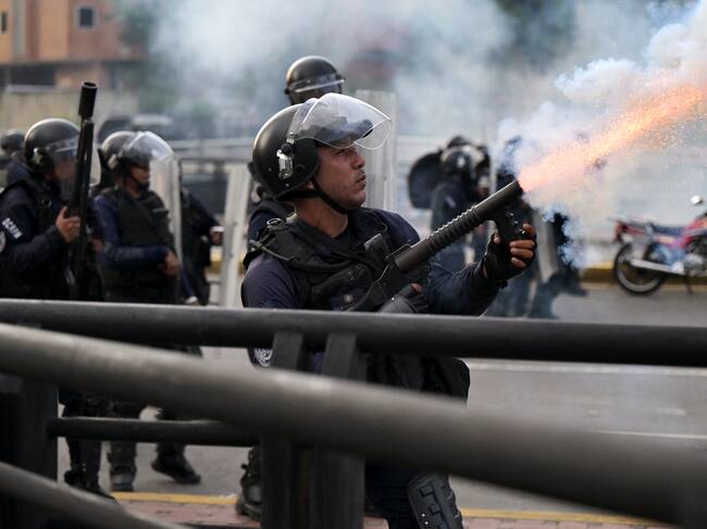 TOPSHOT - A police officer fires tear gas during a protest against President Nicolas Maduro's government in Caracas on July 29, 2024, a day after the Venezuelan presidential election. Protests erupted in parts of Caracas Monday against the re-election victory claimed by Venezuelan President Nicolas Maduro but disputed by the opposition and questioned internationally, AFP journalists observed. (Photo by Yuri CORTEZ / AFP) (Photo by YURI CORTEZ/AFP via Getty Images)