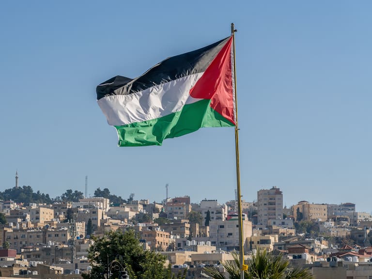 The large Palestinian flag (flag of Palestine) is waiving above the city.