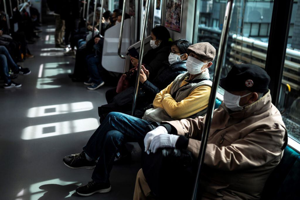 Las personas utilizan mascarillas en el tren en Tokio