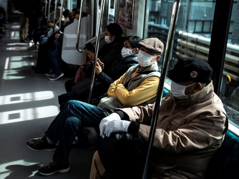 Las personas utilizan mascarillas en el tren en Tokio