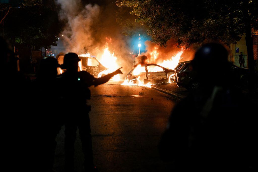 Policías de Francia observan barricada con autos quemados en París