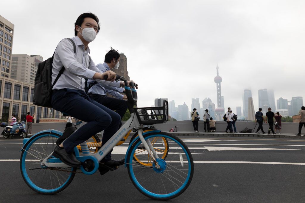 Las personas en bicicleta pasan por un puente de la ciudad de Shanghái