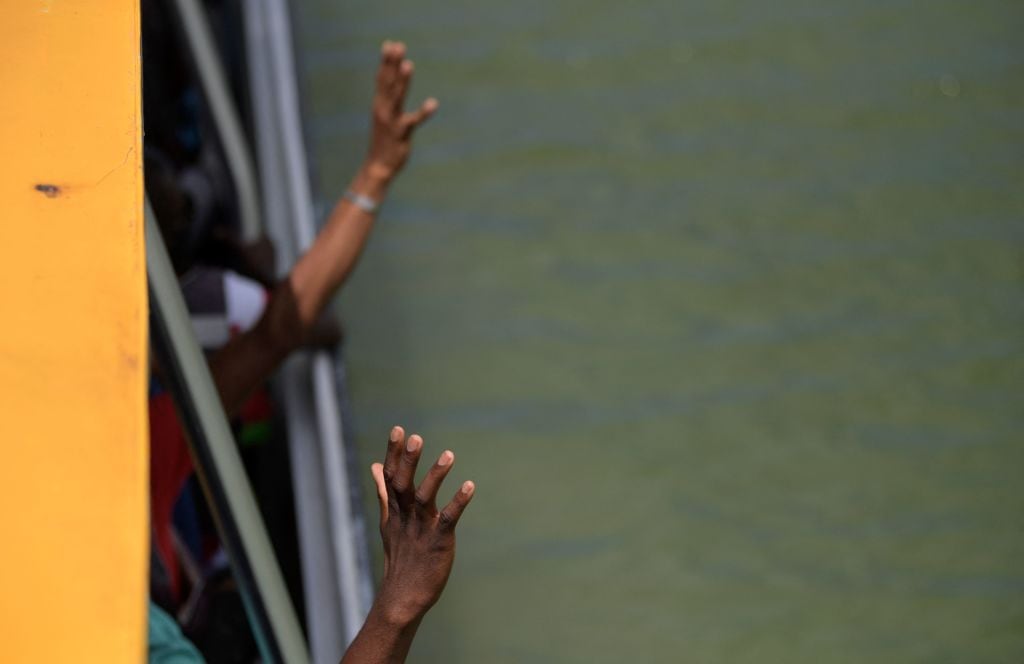 Migrantes haitianos saludan desde el interior de un barco