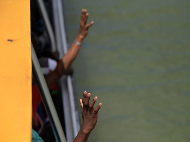 Migrantes haitianos saludan desde el interior de un barco