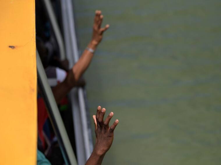 Migrantes haitianos saludan desde el interior de un barco