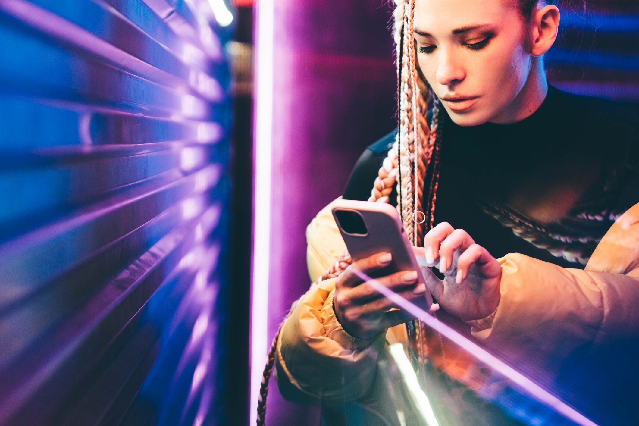 Woman using mobile phone in neon lights.