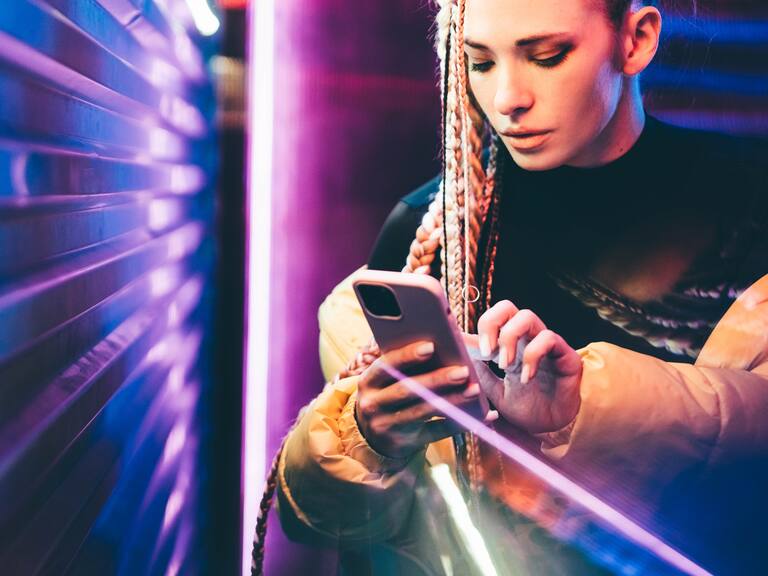 Woman using mobile phone in neon lights.