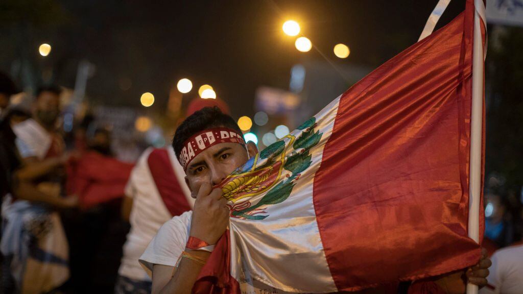 LIMA, PERU - NOVEMBER 14: A protester embraces Peru's national flag during a protest against newly appointed interim president Manuel Merino on November 14, 2020 in Lima, Peru. Thousands of protesters have demonstrated for five days against the new government and dozens were wounded after clashes with police. Manuel Merino de Lama, who was head of National Congress, replaces President Vizcarra after he was ousted by lawmakers over allegations of corruption years ago.  (Photo by Beto Baron/Getty Images)