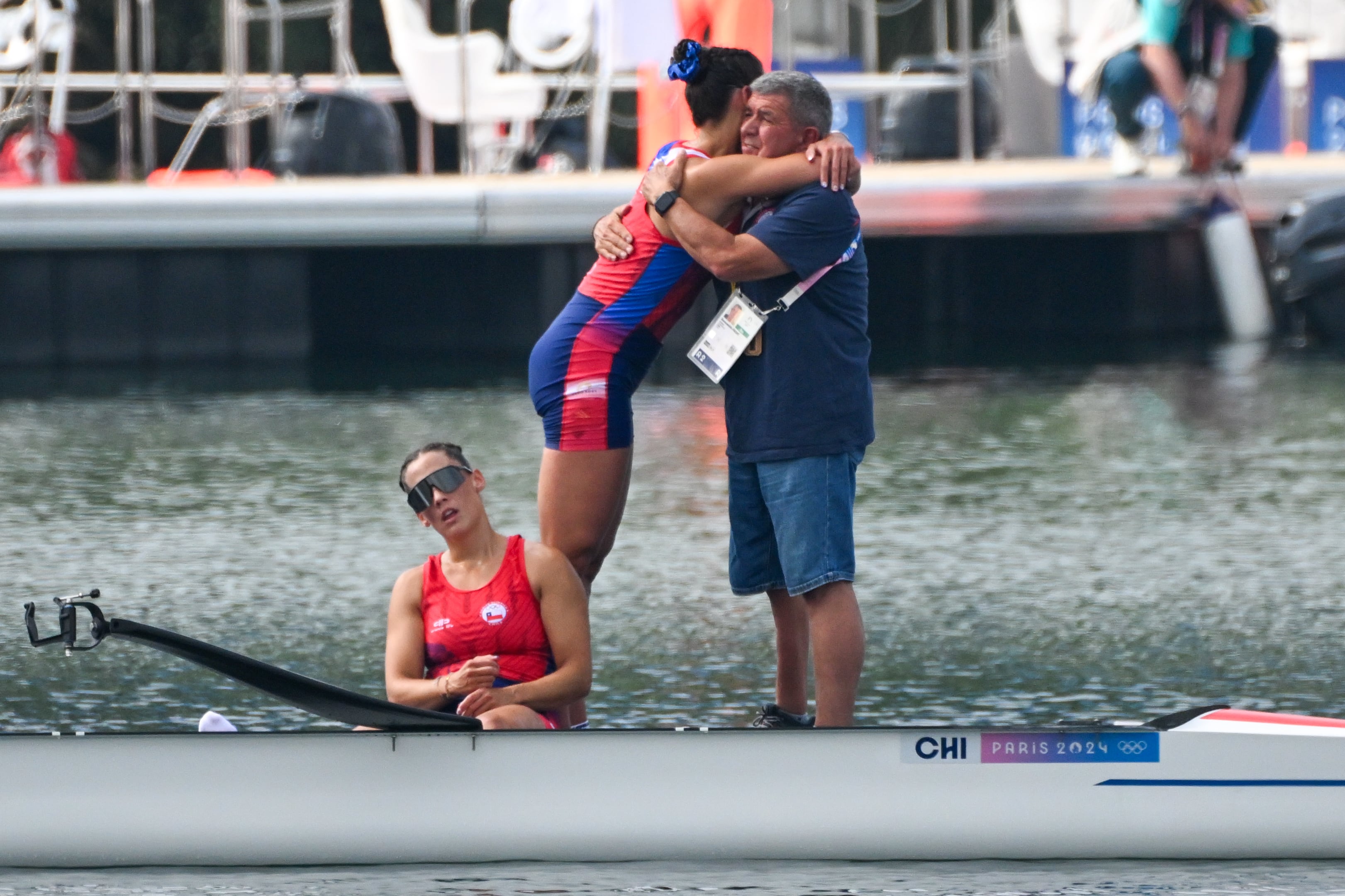 Tras finalizar novenas en el remo, Antonia y Melita Abraham se abrazan con su entrenador, el español Bienvenido Front.