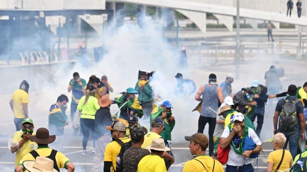 Supporters of Brazilian former President Jair Bolsonaro clash with the police during a demonstration outside the Planalto Palace in Brasilia on January 8, 2023. - Brazilian police used tear gas Sunday to repel hundreds of supporters of far-right ex-president Jair Bolsonaro after they stormed onto Congress grounds one week after President Luis Inacio Lula da Silva's inauguration, an AFP photographer witnessed. (Photo by EVARISTO SA / AFP) (Photo by EVARISTO SA/AFP via Getty Images)