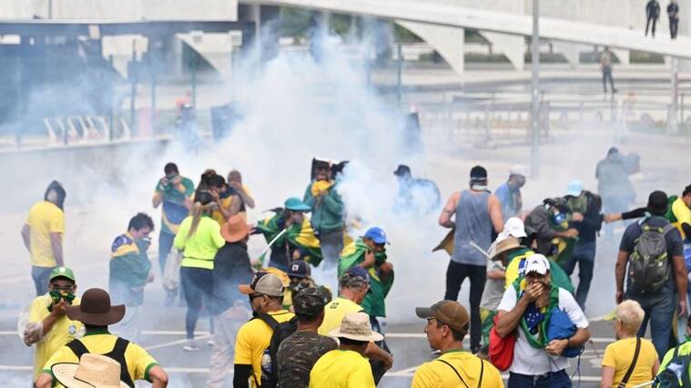 Supporters of Brazilian former President Jair Bolsonaro clash with the police during a demonstration outside the Planalto Palace in Brasilia on January 8, 2023. - Brazilian police used tear gas Sunday to repel hundreds of supporters of far-right ex-president Jair Bolsonaro after they stormed onto Congress grounds one week after President Luis Inacio Lula da Silva's inauguration, an AFP photographer witnessed. (Photo by EVARISTO SA / AFP) (Photo by EVARISTO SA/AFP via Getty Images)