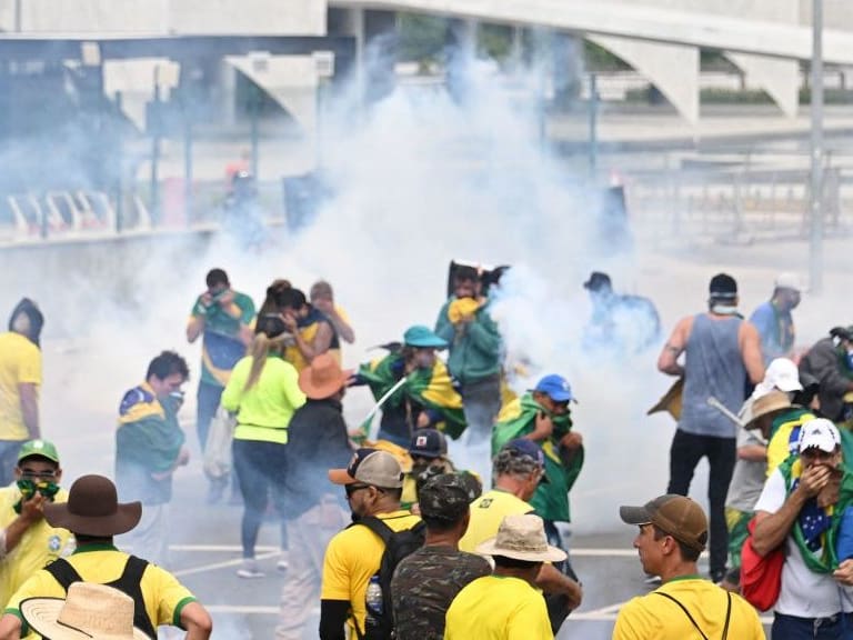 Supporters of Brazilian former President Jair Bolsonaro clash with the police during a demonstration outside the Planalto Palace in Brasilia on January 8, 2023. - Brazilian police used tear gas Sunday to repel hundreds of supporters of far-right ex-president Jair Bolsonaro after they stormed onto Congress grounds one week after President Luis Inacio Lula da Silva&#039;s inauguration, an AFP photographer witnessed. (Photo by EVARISTO SA / AFP) (Photo by EVARISTO SA/AFP via Getty Images)