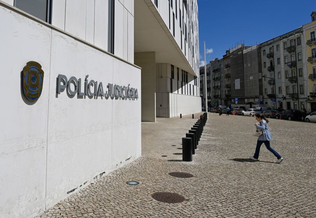 Una mujer camina en la ciudad de Lisboa hacia el ingreso de la sede de la Policía Judicial de Portugal.