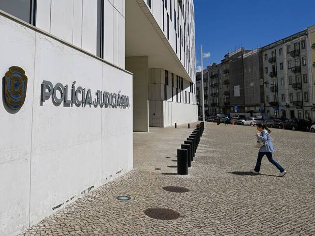 Una mujer camina en la ciudad de Lisboa hacia el ingreso de la sede de la Policía Judicial de Portugal.