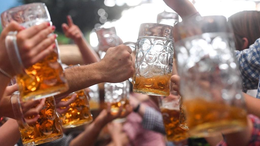 Visitors of the Oktoberfest beer festival clink their beer glasses on September 24, 2017 at the Theresienwiese fair grounds in Munich, southern Germany.The World's largest beer festival takes place until October 3, 2017. / AFP PHOTO / dpa / Tobias Hase / Germany OUT (Photo credit should read TOBIAS HASE/DPA/AFP via Getty Images)