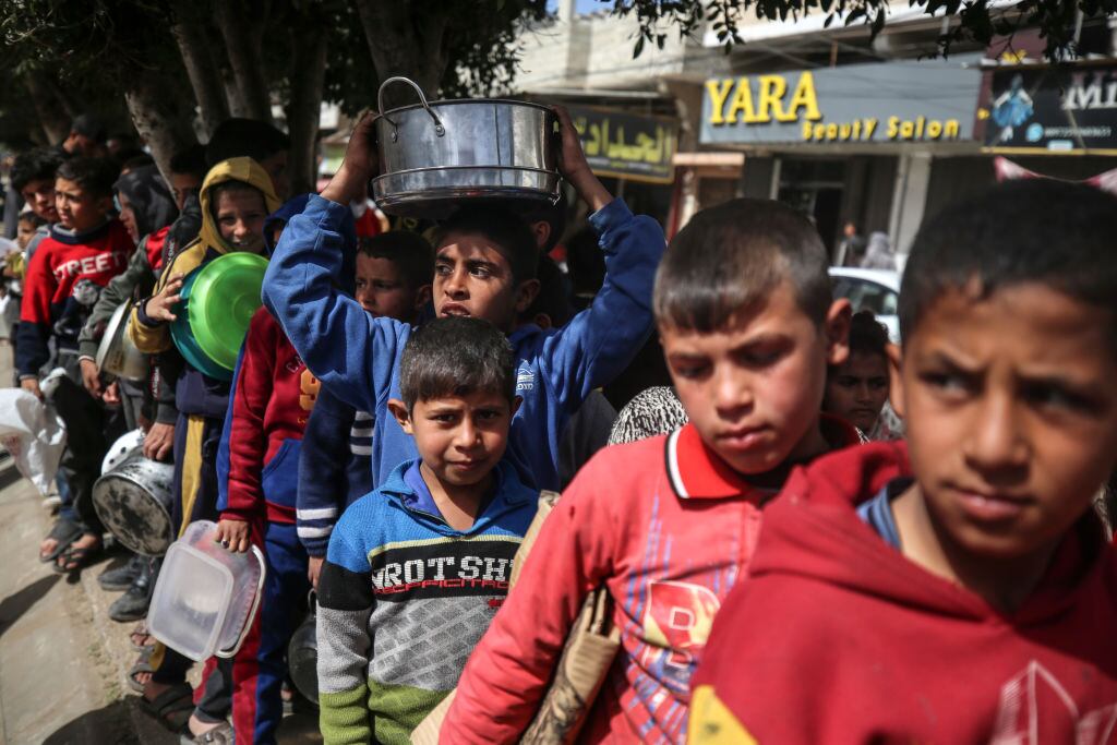 Niños refugiados palestinos esperan por la entrega de alimento en las calles de la Franja de Gaza en Palestina, en medio de los ataques armados de Israel.