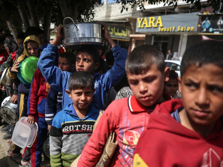 Niños refugiados palestinos esperan por la entrega de alimento en las calles de la Franja de Gaza en Palestina, en medio de los ataques armados de Israel.