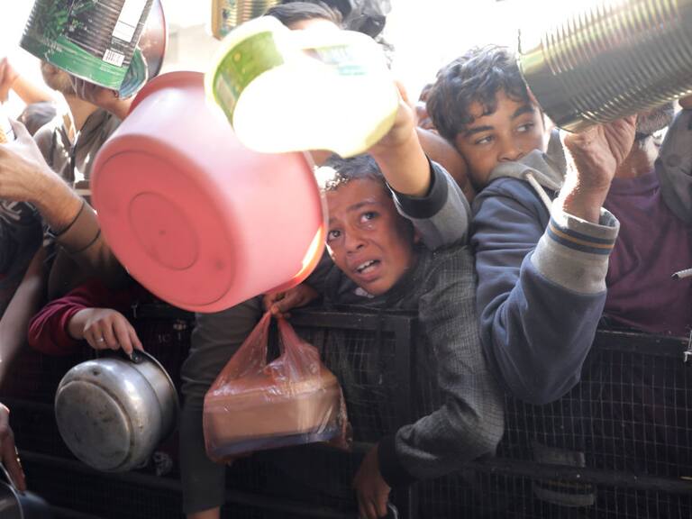 Niños, mujeres y hombres buscan alimentos para colocar en sus inventados plato de comida en la Franja de Gaza en Palestina
