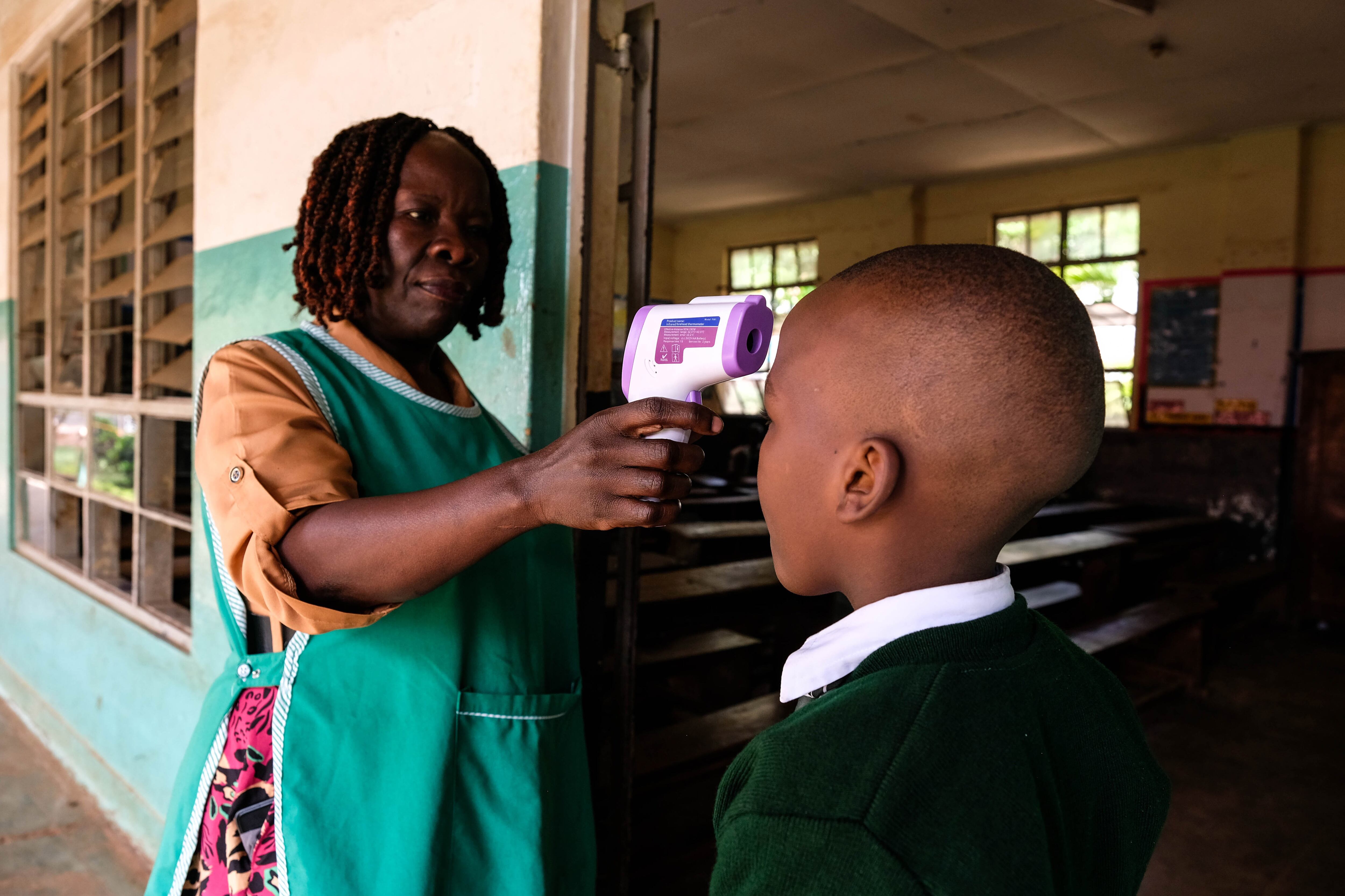KAMPALA, UGANDA - MAY 25: The school nurse checking pupil's temperature before he enters class at Nakasero Primary School on the day of reopening amid the Ebola outbreak on May 25, 2026 in Kampala, Uganda. Ugandan health authorities are implementing preparedness and response measures following the confirmation of three additional Ebola Bundibugyo cases in the country, bringing the total to five. The cases have been linked to individuals and contacts of individuals who traveled from the neighboring Democratic Republic of Congo (DRC), which has seen an outbreak of 904 suspected cases and 119 suspected deaths in the Ituri and North Kivu provinces. The World Health Organization (WHO) has declared the Ebola outbreak in the DRC and Uganda a public health emergency of international concern. (Photo by Hajarah Nalwadda/Getty Images)