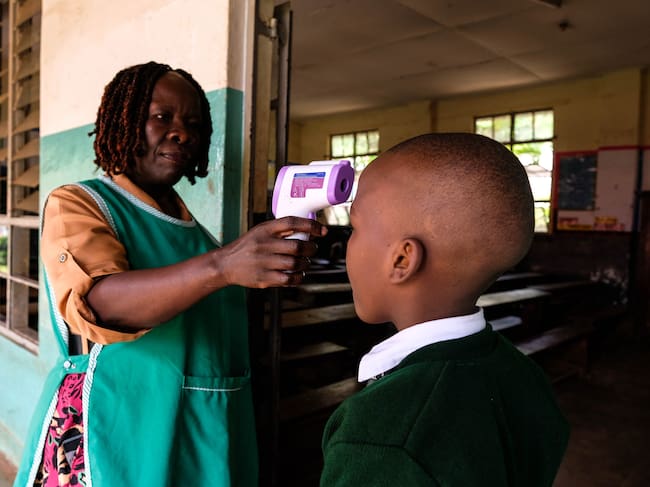 KAMPALA, UGANDA - MAY 25: The school nurse checking pupil's temperature before he enters class at Nakasero Primary School on the day of reopening amid the Ebola outbreak on May 25, 2026 in Kampala, Uganda. Ugandan health authorities are implementing preparedness and response measures following the confirmation of three additional Ebola Bundibugyo cases in the country, bringing the total to five. The cases have been linked to individuals and contacts of individuals who traveled from the neighboring Democratic Republic of Congo (DRC), which has seen an outbreak of 904 suspected cases and 119 suspected deaths in the Ituri and North Kivu provinces. The World Health Organization (WHO) has declared the Ebola outbreak in the DRC and Uganda a public health emergency of international concern. (Photo by Hajarah Nalwadda/Getty Images)