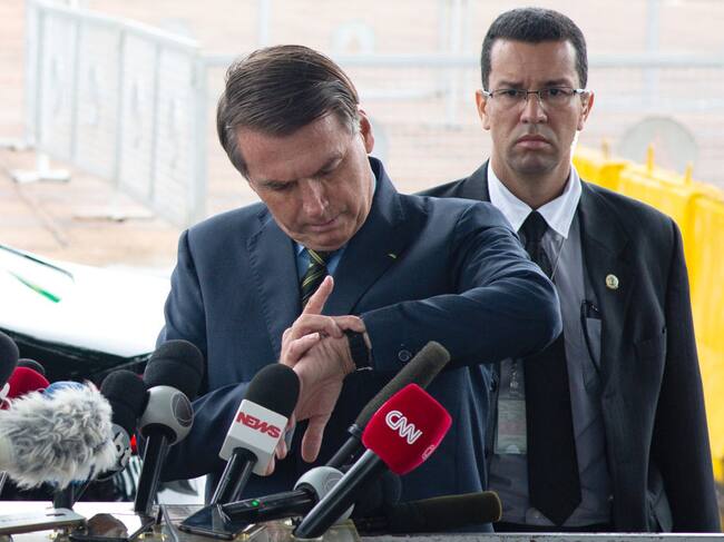 Jair Bolsonaro intenta ver la hora en una conferencia en Brasilia