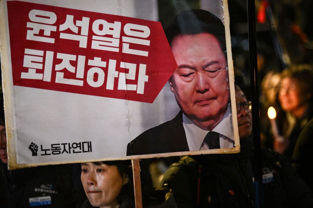 Mujer porta un cartel en la ciudad de Seúl pidiendo la renuncia del presidente Yoon Suk Yeol tras su fallido intento de decretar la ley marcial en Corea del Sur
