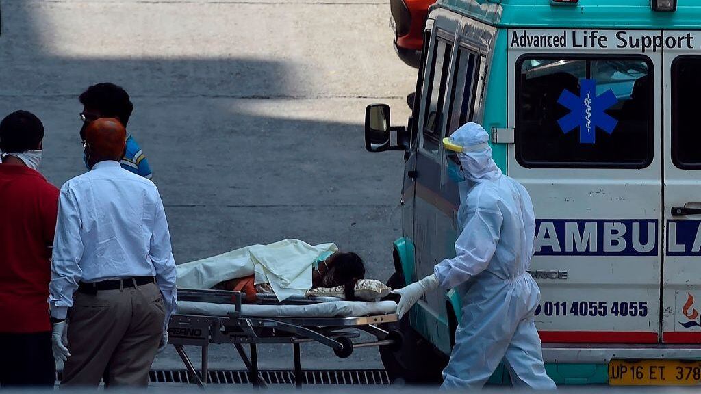 Trabajadores de la salud transportan a un paciente de Covid-19 en India