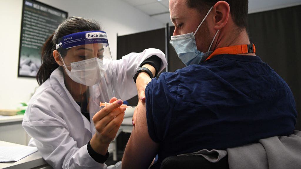 BOREHAMWOOD, ENGLAND - FEBRUARY 15: Care worker Jordan Lewis (R) receives the Oxford-AstraZeneca Covid-19 vaccine at the Med Mart pharmacy on February 15, 2021 in Borehamwood, England. (Photo by Karwai Tang/Getty Images)