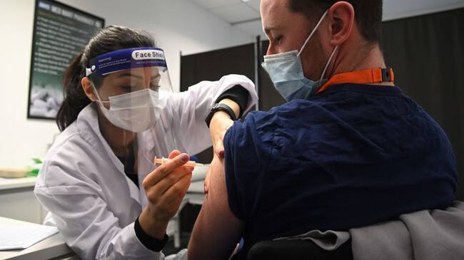 BOREHAMWOOD, ENGLAND - FEBRUARY 15: Care worker Jordan Lewis (R) receives the Oxford-AstraZeneca Covid-19 vaccine at the Med Mart pharmacy on February 15, 2021 in Borehamwood, England. (Photo by Karwai Tang/Getty Images)