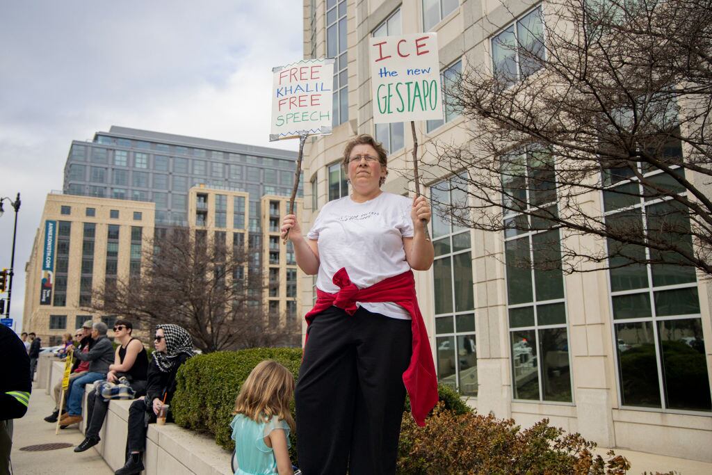 A protester stands outside the ICE building holding signs during a demonstration in Washington, DC, on March 15, 2025. The Palestinian Youth Movement organized the rally to demand the release of Mahmoud Kalil, a Palestinian student activist facing deportation from the United States. (Photo by Hanna Leka / Middle East Images / Middle East Images via AFP) (Photo by HANNA LEKA/Middle East Images/AFP via Getty Images)          