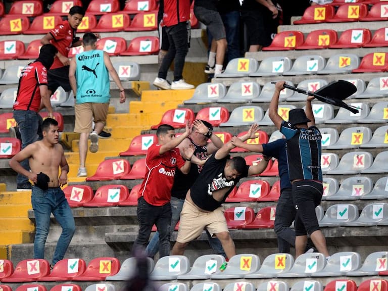 Supporters of Atlas fight with supporters of Queretaro during the Mexican Clausura tournament football match between Queretaro and Atlas at Corregidora stadium in Queretaro, Mexico on March 5, 2022. - A match between Mexican football clubs was called off March 5, 2022 after violence by opposing fans spilled onto the field. The game between Queretaro and Atlas at La Corregidora stadium in the city of Queretaro -- the ninth round of the 2022 Clausura football tournament -- was in its 63rd minute when fights between opposing fans broke out. (Photo by AFP) (Photo by STR/AFP via Getty Images)