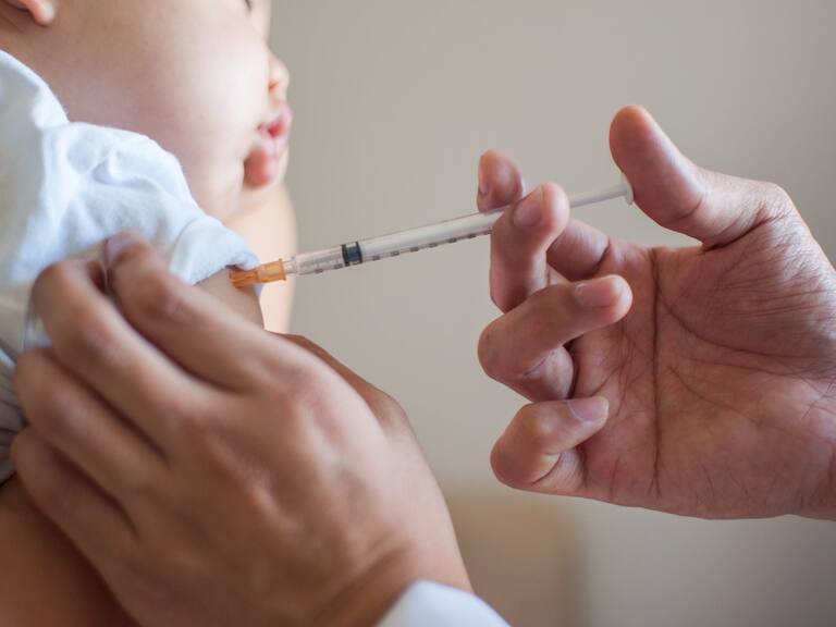 A doctor is injecting a vaccine to a baby boy indoor