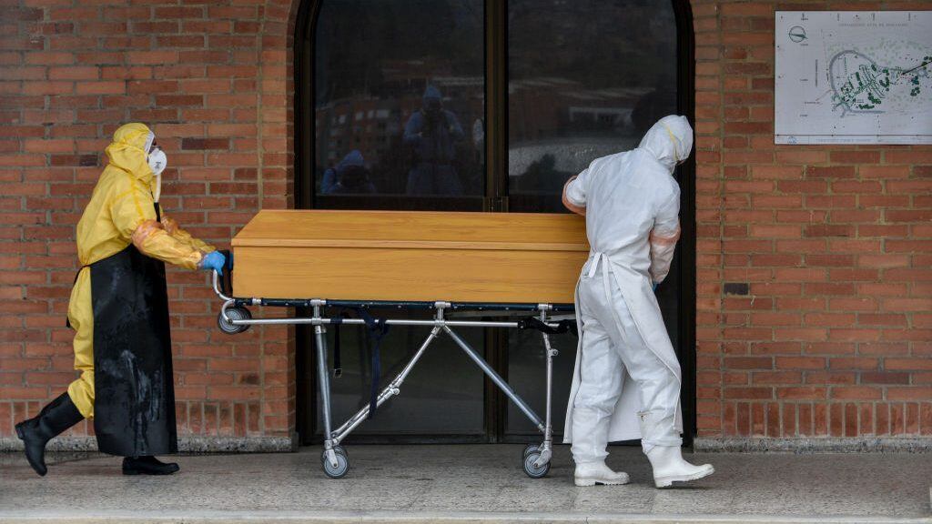 BOGOTA, COLOMBIA - JULY 04: Funeral workers wearing PPE transport a coffin with the remains of a deceased by COVID-19 at the entrance of the crematorium before being cremated at Parque Serafin cemetery on July 04, 2020 in Bogota, Colombia. The Parque Serafin Cemetery is one of the largest in Bogotá, the most affected city by contagion in the country, where most confirmed or suspected COVID-19 victims were cremated following strict health protocols. The cemetery has cremated up to 18 remains per day. (Photo by Guillermo Legaria/Getty Images)