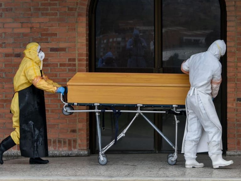 BOGOTA, COLOMBIA - JULY 04: Funeral workers wearing PPE transport a coffin with the remains of a deceased by COVID-19 at the entrance of the crematorium before being cremated at Parque Serafin cemetery on July 04, 2020 in Bogota, Colombia. The Parque Serafin Cemetery is one of the largest in Bogotá, the most affected city by contagion in the country, where most confirmed or suspected COVID-19 victims were cremated following strict health protocols. The cemetery has cremated up to 18 remains per day. (Photo by Guillermo Legaria/Getty Images)