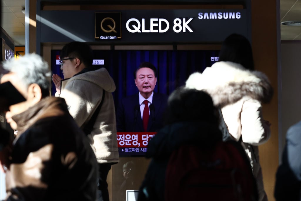Las personas caminan cerca de un televisor en la ciudad de Seúl donde se muestran noticias del presidente de Corea del Sur, Yoon Suk Yeol