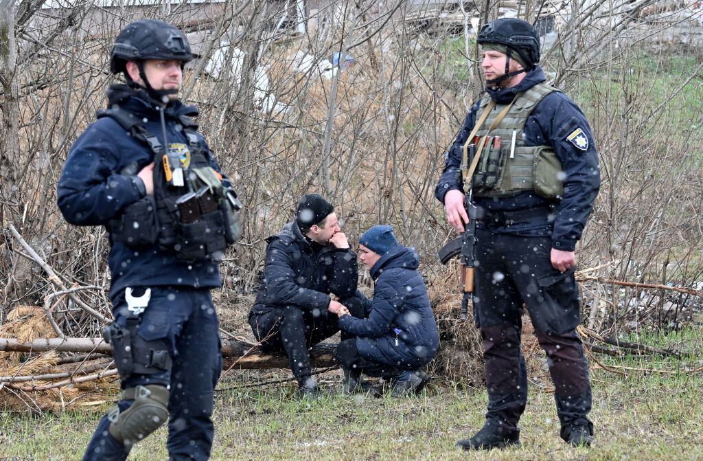 TOPSHOT - People react as they gather close to a mass grave in the town of Bucha, just northwest of the Ukrainian capital Kyiv on April 3, 2022. - President Volodymyr Zelensky accused Russia of committing genocide and attempting to eliminate the "whole nation" of Ukraine, a day after the discovery of mass graves and apparently executed civilians near Kyiv. (Photo by Sergei SUPINSKY / AFP) (Photo by SERGEI SUPINSKY/AFP via Getty Images)