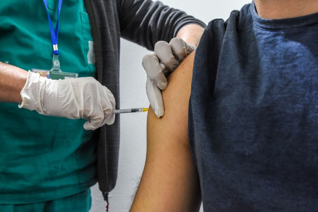 Trabajador de la salud vacuna a una persona en Palermo