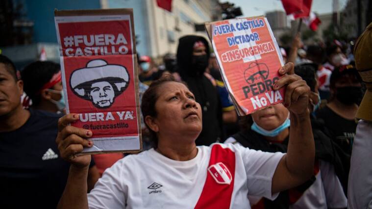 A woman holds signs during a protest against the governement of Peru's President Pedro Castillo, in Lima on April 05, 2022 - Peruvian President Pedro Castillo announced the end of a curfew in the capital Lima aimed at containing protests against rising fuel prices following crisis talks with Congress. (Photo by ERNESTO BENAVIDES / AFP) (Photo by ERNESTO BENAVIDES/AFP via Getty Images)