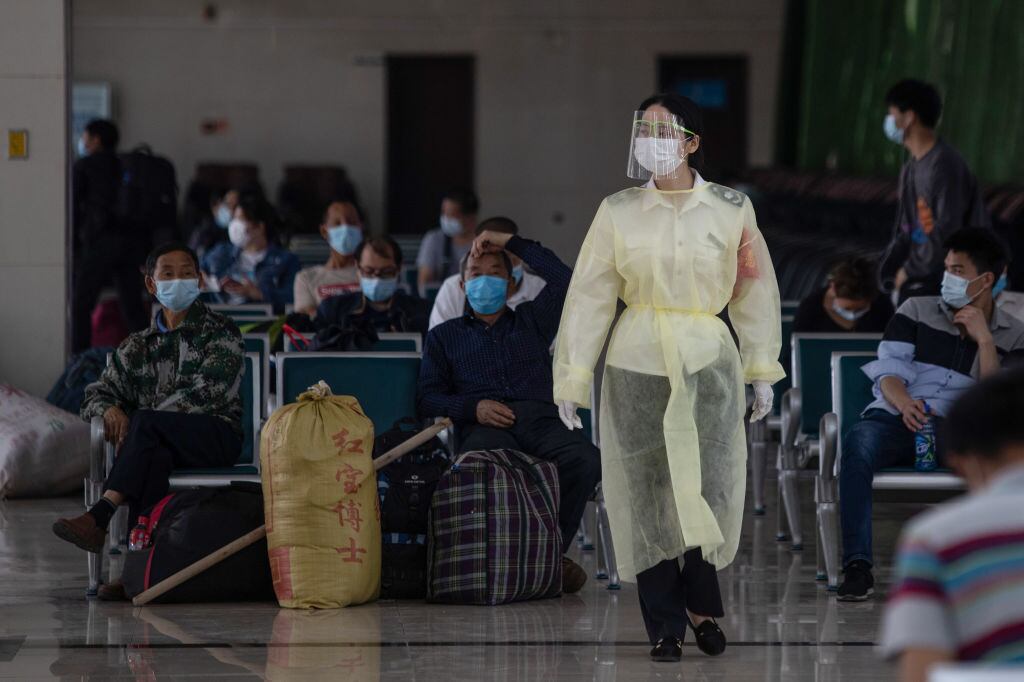 Una trabajadora utiliza un traje de protección en un terminal de buses de China
